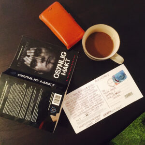 Boken ligger på ett bord med kaffekopp och telefon